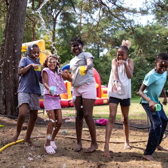 5 kinderen spelen op wollebos met water