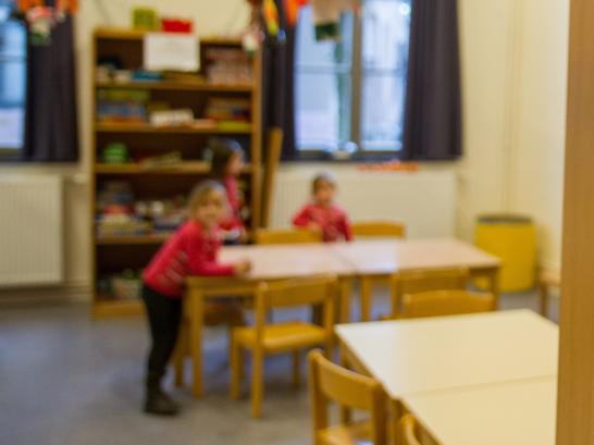 3 kinderen spelen in de verte aan tafel kinderopvang