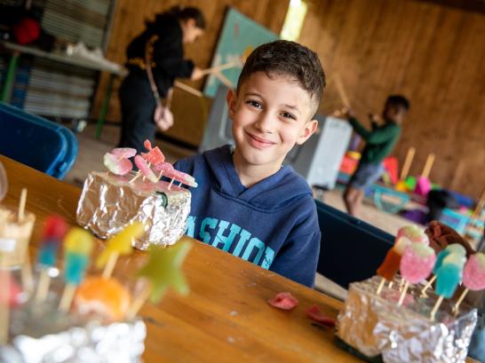2 kinderen poseren trots bij hun zelfgemaakte snoeptaart op Wollebos
