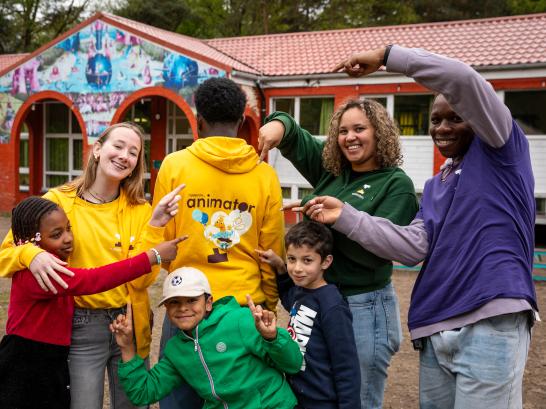 Verschillende types wollebos animatoren wijzen naar een animator t-shirt samen met kinderen