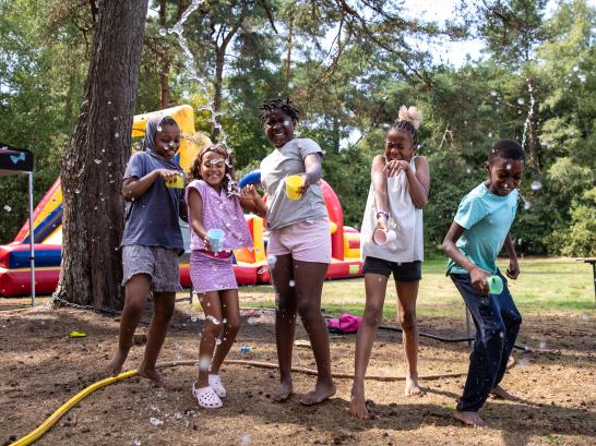 5 kinderen spelen op wollebos met water