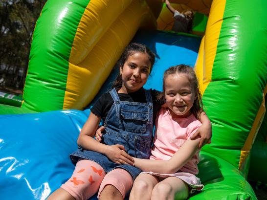 2 meisjes lachen in camera op springkasteel