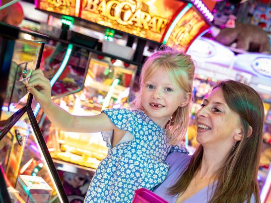 Meisje en mama spelen samen in het Lunapark op de kermis