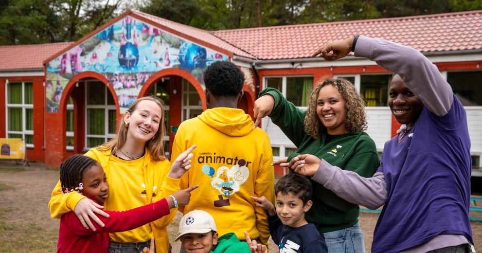 Verschillende types wollebos animatoren wijzen naar een animator t-shirt samen met kinderen