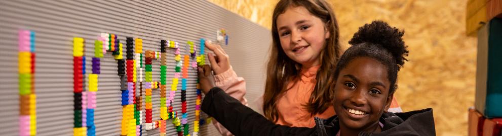 2 kinderen bouwen met legoblokjes het woord Wollebos