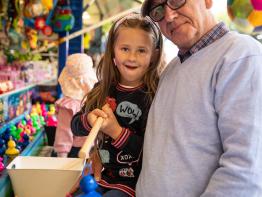 Kind en opa vangen eendjes op de kermis
