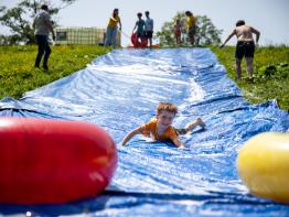 Jongen glijdt van waterschuifbaan op Binkies Kinderfestival