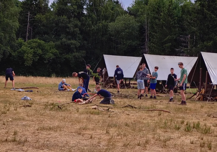 Foto van een tenten op een veld en spelende kinderen die met de jeugdvereniging op kamp zijn